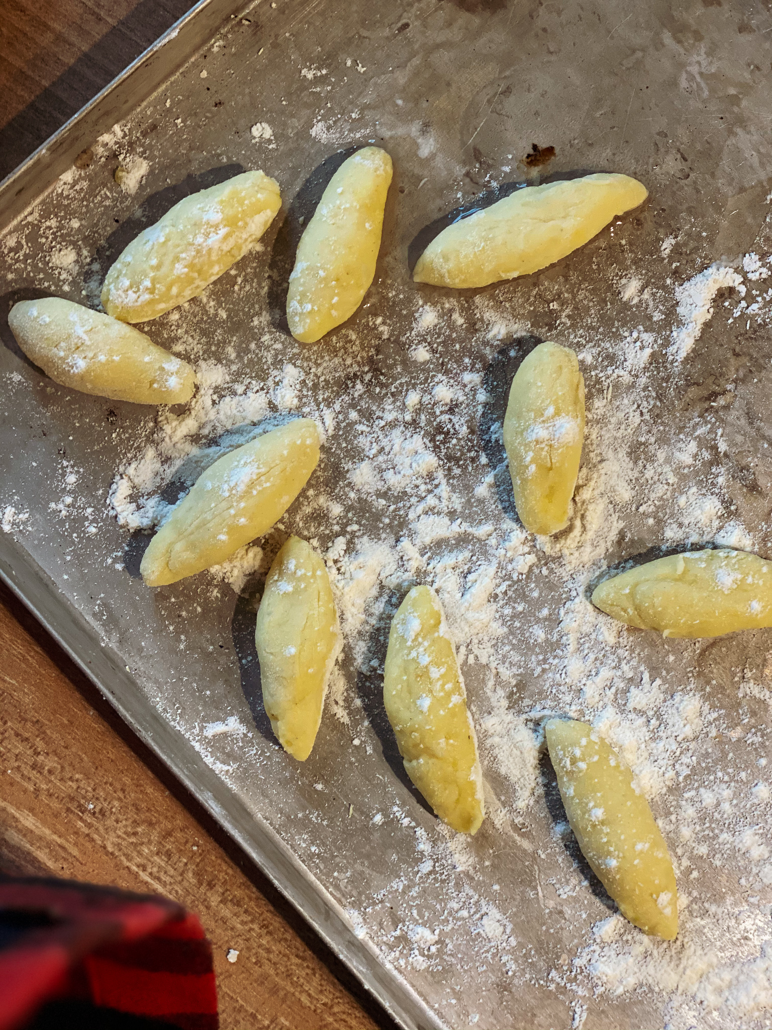 Schupfnudeln roh Rohlinge von Schupfnudeln auf einem bemehlten Backblech, bereit zur weiteren Verarbeitung.