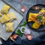 Hausgemachte Maultaschen mit würziger Gruyère-Füllung, angerichtet mit gebratenen Zwiebeln und frischer Petersilie