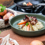 Cremiges Bier-Risotto mit gerösteten Karotten und knusprigem Speck auf einem Teller serviert